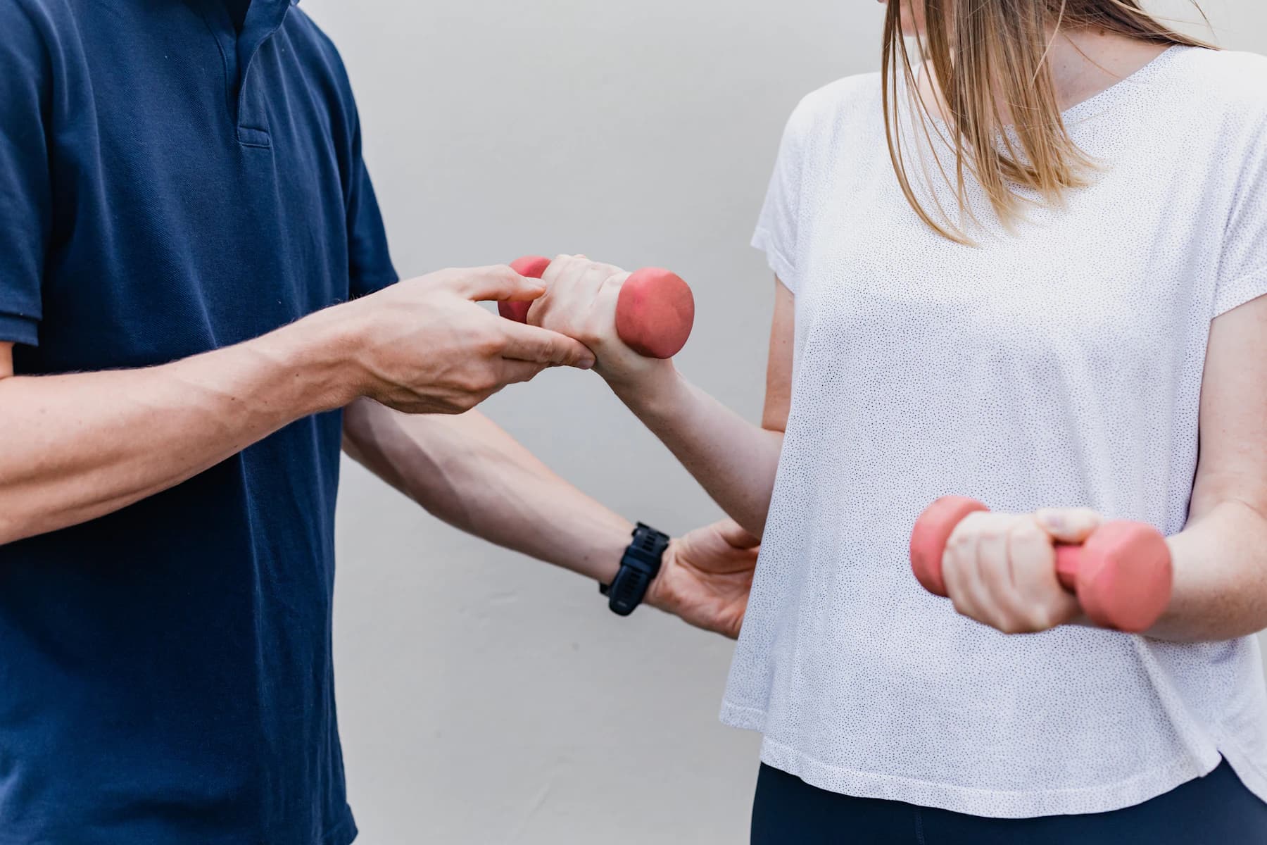 A physiotherapist guiding a patient's arm as she lifts a light dumbbell